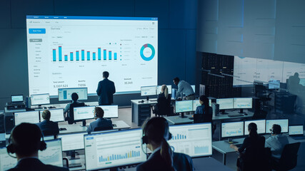 Professional Traders Working in a Modern Monitoring Office with Live Analytics Feed on a Big...