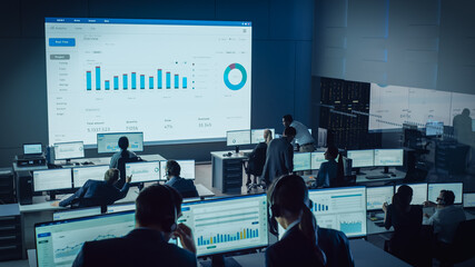 Professional Traders Working in a Modern Monitoring Office with Live Analytics Feed on a Big...