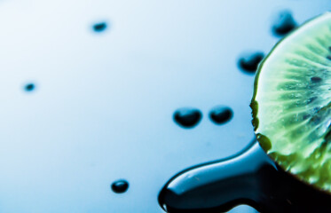 Macro closeup detail of a half slice juicy green fresh tropical kiwi on blue and white background with copy-space