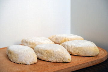 Raw handmade pies on a wooden plate. Bakery products. Dough blanks. Second courses.
