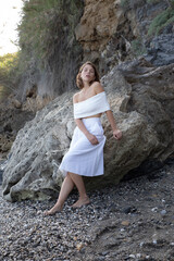 Natural beauty of as young lady Posing in the shore of the coast side in a tourist location with rocks background