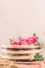 Chocolate naked cake with fresh roses and swiss buttercream on a white background