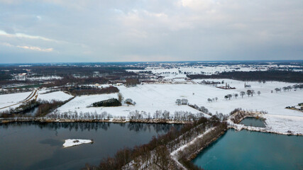 Aerial view with a drone of a spring wavy agricultural countryside landscape with plowed and unplowed fields and trees in the blue evening sky. High quality photo