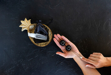 A woman holds black vaginal balls ready for muscles exercises. Strong vaginal muscles