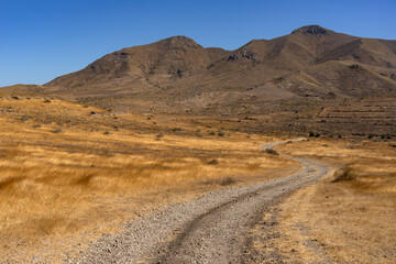 Fototapeta premium Panoramic view of of mountains with a dirt road in the Gata Cape Natural Park coast. Almería, Andalucía, Spain.