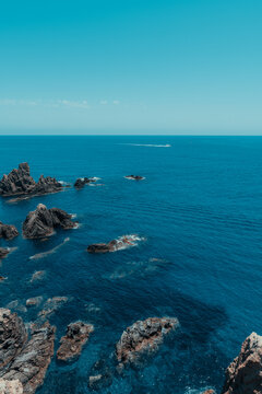 Mar azul en verano con acantilados y rocas. Agua cristalina y una lancha al fondo. Cabo de gata, Almer&iacute;a.