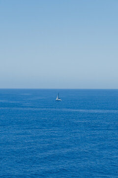 Mar azul en verano con un barco velero en medio de la imagen.