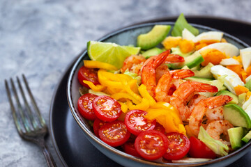 Delicious fresh salad with prawns, avocado, eggs, bell pepper, tomatoes and herbs