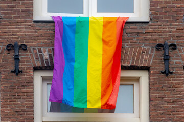 Celebration of Pride month, Colourfull rainbow flag hanging outside  the window of building, The symbol of lesbian, gay, bisexual and transgender, LGBTQ community in Amsterdam, Netherlands.