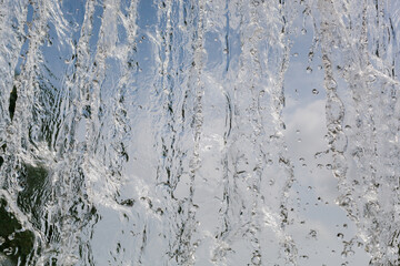 inside view of the falling water of the waterfall against the blue sky. water in motion