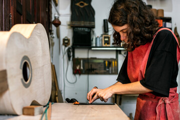 woman luthier making guitars in her musical instrument workshop