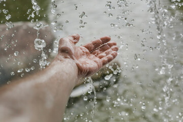 Fototapeta premium splashing water falling on a man's hand from a waterfall