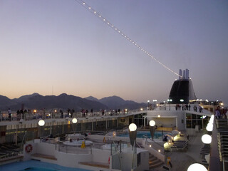 View over pool sun deck promenade on modern cruiseship cruise ship liner during twilight