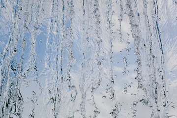 inside view of the falling water of the waterfall against the blue sky. water in motion