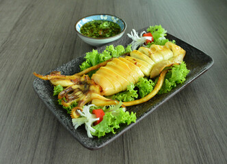 bbq grill squid octopus seafood with spicy chilli sauce in hot pot on wood table asian halal menu