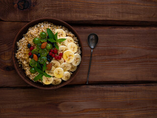 Wholegrain Oatmeal porridge bowl with fresh berries, fruits, nuts mint leaves flat lay. Healthy...
