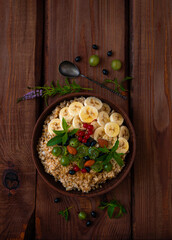 Wholegrain Oatmeal porridge bowl with fresh berries, fruits, nuts mint leaves flat lay. Healthy food oat meal morning breakfast top view. Whole grain cereal gooseberry currant banana on wooden table.