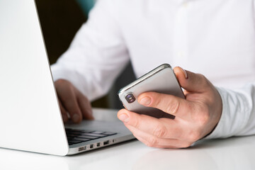 close up of male hands typing on laptop keyboard while working at white desk