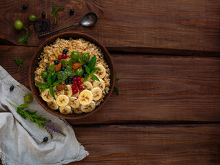 Wholegrain Oatmeal porridge bowl with fresh berries, fruits, nuts mint leaves flat lay. Healthy...