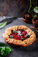 Powdered sugar is poured onto homemade pie with strawberries on the table, summer pastries with berries, vertical photo with copy space for text