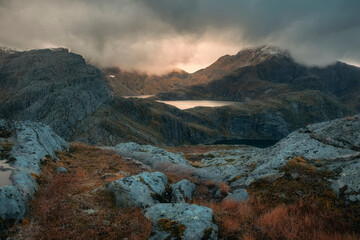 Obraz premium Sun shining through rain clouds over a lake in the Norwegian mountains on the Lofoten Islands