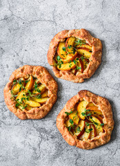 Peaches, fresh thyme mini pies - delicious summer pastry dessert on a grey background, top view