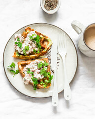 Savory potato herbs waffles with tuna, cream cheese pate and coffee on a light background, top view