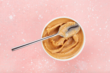 smooth peanut butter in bowl on pink background