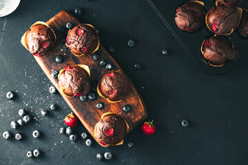 Muffin. Chocolate muffins with stawberry. Muffins on wooden stand. © Exploder