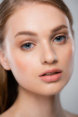 Obraz premium close up of young woman with perfect skin looking at camera isolated on grey