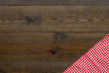 Red picnic cloth on wooden table, top view