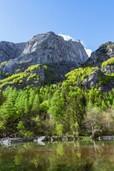 A small alpine lake during spring in val di mello, among the Italian alps, near the town of San Martino, Italy - may 2021