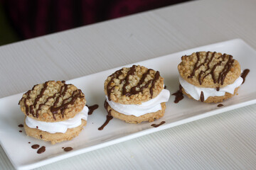 A cookie and cream sandwich. Decorated with chocolate. Lies on a plate.