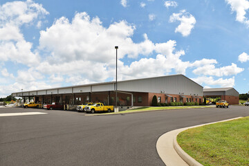 Fototapeta na wymiar Generic brick business industrial warehouse building parking lot with yellow trucks