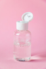 Bottle with micellar cleansing water on pink background. Skin care concept.
