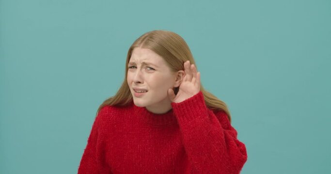Skeptic young woman with long blond hair asking to repeat as she hears only nonsense