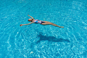 View of slim woman lies on a water surface in the crystal pool