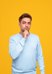 Thoughtful man rubbing chin and looking at camera