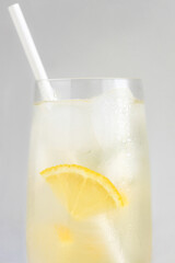 Close up of glass of lemonade or lemon water with paper straw.