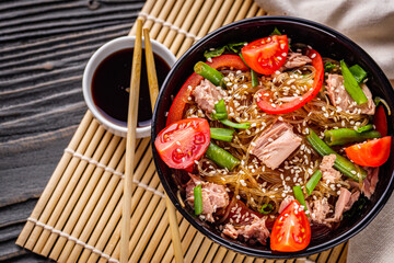 delicious glass noodles with tuna and vegetables on a dark wooden rustic background