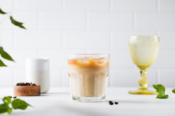 Cold coffee with ice and cream on a white tile background. Homemade cold latte. 