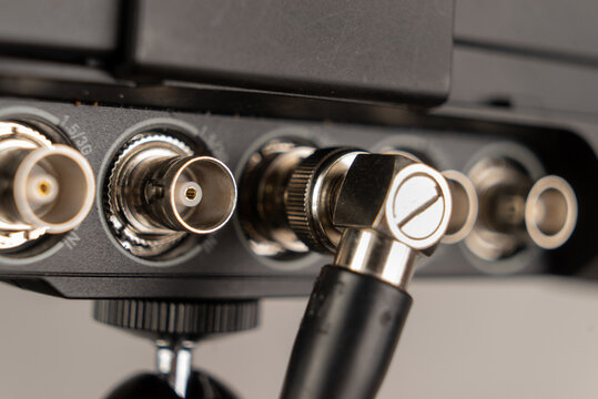 Metal locking connector of an SDI cable with angled head connected to the terminal input 3g port on back of Atomos Shogun Inferno 4K RAW video signal recording monitor connected to camera