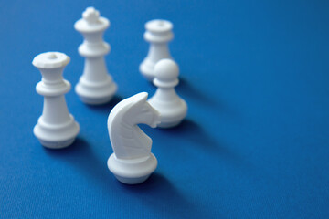 Teamwork concept. White chess pieces on a blue background. Pawn, chess knight and chess queen on a bright background. Team building concept