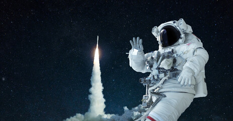 Space man in a space suit and hat travels in open space and waves his hand against the background...