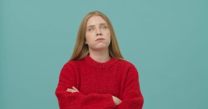 Young woman with long blond hair rolling eyes and feeling bored isolated over blue background