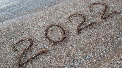 the figures of the new year 2022 are written on the sand on the beach. the next year of the tiger