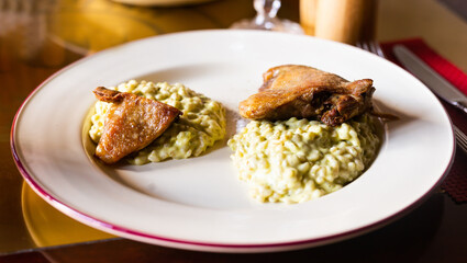 dish duck leg with green perlotto served on a white plate