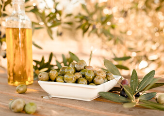 green olives and oil on table in olive grove