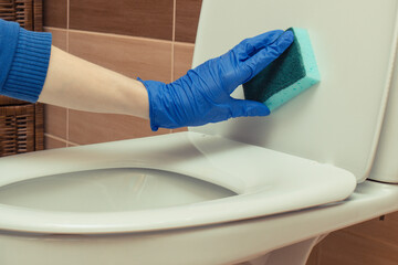 Hand of cleaner using sponge for cleaning toilet. Household duties concept