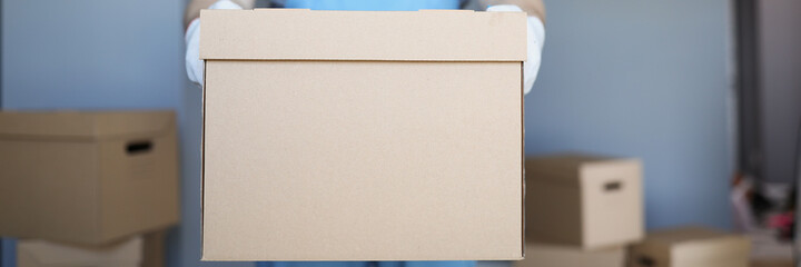 Fototapeta premium Male courier is holding large cardboard box